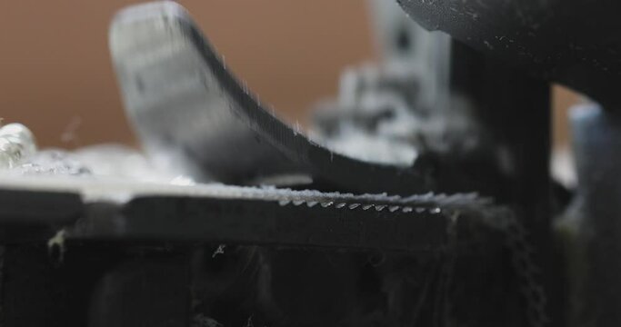 macro of a foot with an overlock needle that sews fabric in the production of clothing. movement of the sewing machine. close-up