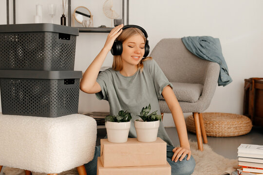 Attractive girl is moving her stuff around in her new apartment. Young woman is listening to music and having great time. Concept of moving