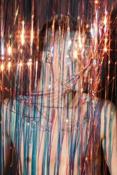 Anonymous man behind colorful tinsel
