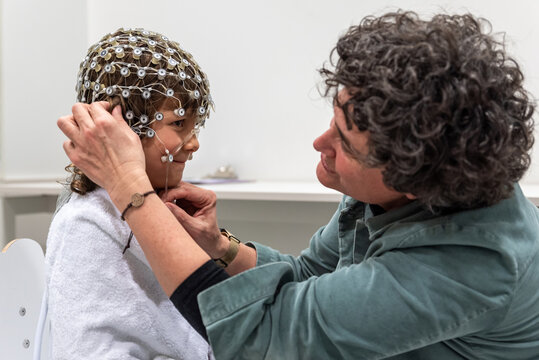 Medical personnel preparing crying child for EEG test