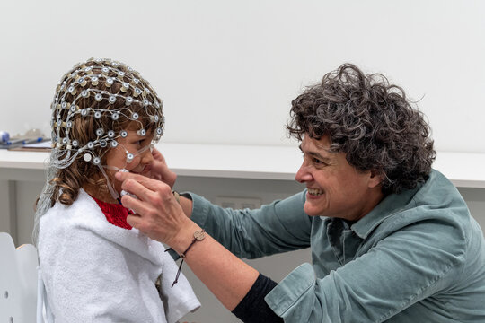 Medical personnel preparing crying child for EEG test