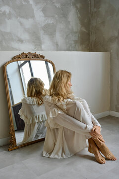 a woman is sitting on the floor in a nightgown