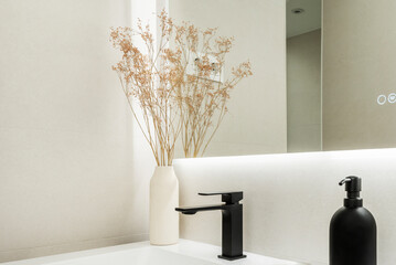 Modern bathroom with white glass countertop, black taps, recessed mirror with anti-bath and decorative vase
