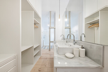 Fototapeta na wymiar Bathroom of a bedroom with a dressing room with a white marble top with gray veining, a double white porcelain sink, a large long mirror and a shower in the background