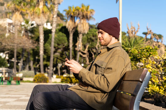 Portrait of man sitting on bench using phone 