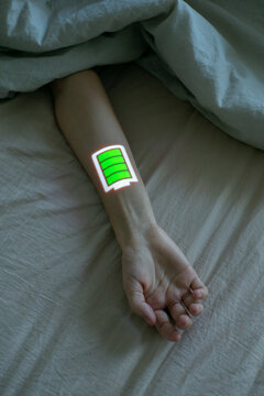 Rest in bed. Human hand with full battery symbol