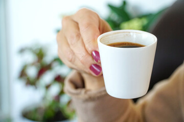 Turkish coffee concept idea, Woman hand holding traditional Turkish coffee cup. Selective focus on cup