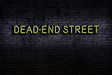 Neon sign. Word dead-end street against brick wall. Night view