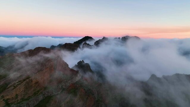 Top view of mountains of Madeira island. Fog moving fast over the mountains. Madeira island covered by clouds. Aerial view of Madeira mountains covered by cumulus clouds in the morning light.