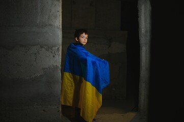 Obraz na płótnie Canvas Russia's war against Ukraine in 2022. A sad boy is hiding in a bomb shelter from Russian missiles. Stop the war.
