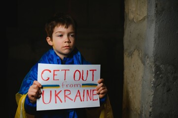 Upset Ukrainian poor toddler boy kid homeless protesting war conflict raises banner with inscription massage text No War on black background. Crisis, peace, stop aggression, child against Russian war