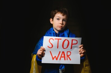 Upset Ukrainian poor toddler boy kid homeless protesting war conflict raises banner with...
