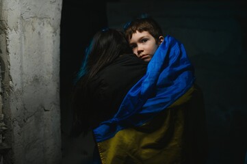 Families against war. Upset Ukrainian boy with his mother, with bue yellow flag, protesting war...