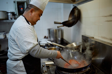 Chinese chef prepares sauce in a restaurant kitchen