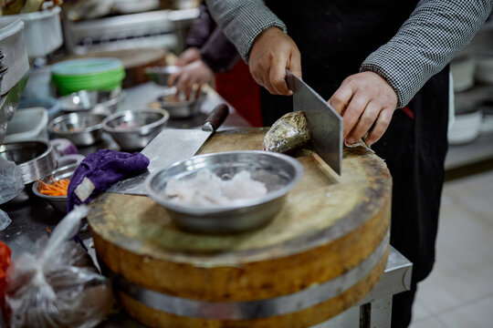 Chinese chef prepares fish in a restaurant kitchen