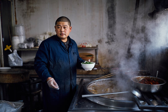 Chinese chef prepares beef soup in a restaurant kitchen