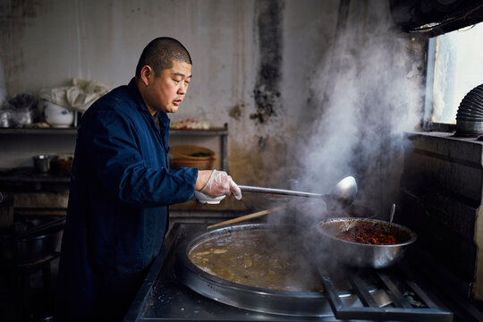 Chinese chef prepares beef soup in a restaurant kitchen - Powered by Adobe