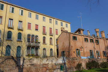 Detail of the old Venetian palaces. Popular buildings behind the red brick wall.