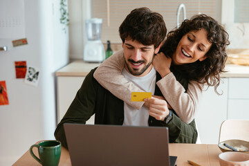 Happy couple making purchase online with plastic card