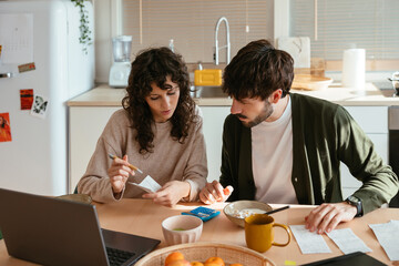 Serious couple paying bills at home
