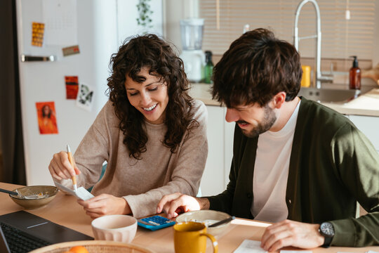 Cheerful couple paying bill at home