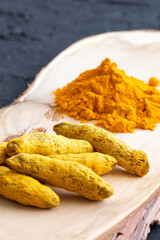 Turmeric curcurmin powder spice and dried root of turmeric on a wooden background. Vegan and healthy food. Organic food.Curcuma powder.Vertical orientation