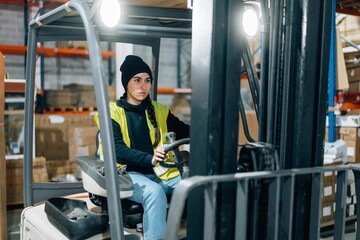 Storehouse worker riding electric forklift