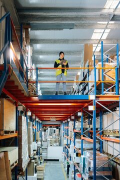 Employee using tablet between racks in storehouse