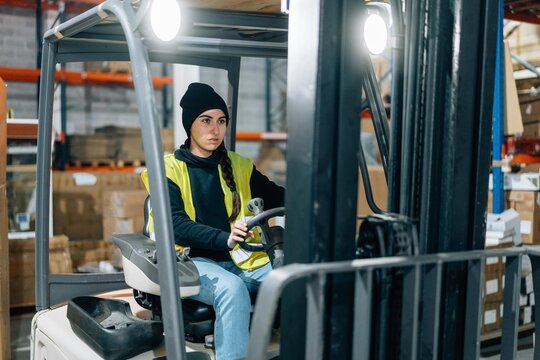 Storehouse worker riding electric forklift