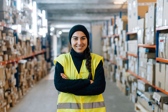 Smiling woman standing between racks in warehouse