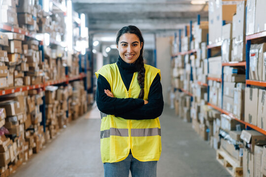 Smiling woman standing between racks in warehouse