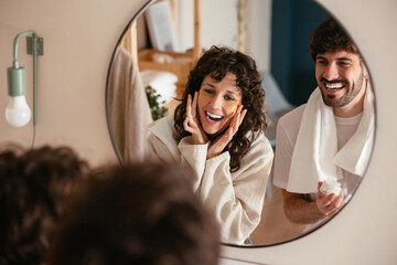 Delighted couple doing skin care treatment in bathroom