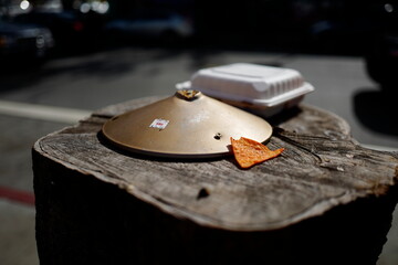 Still life with gold cymbal or some kind of metal cap, a chip and a to-go container. - Powered by Adobe