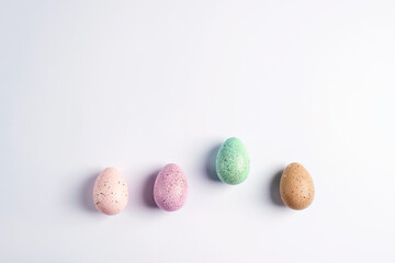 Four colorful decorated Easter eggs on white background. Top view, flat lay, copy space