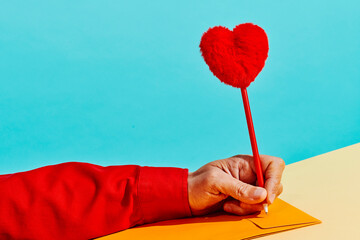 man writing a pen topped with a plush heart