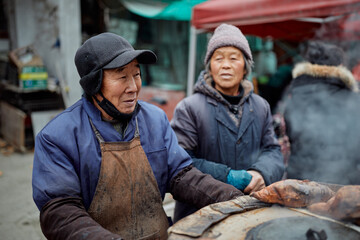 Older Chinese sweet potato vendors at a local market