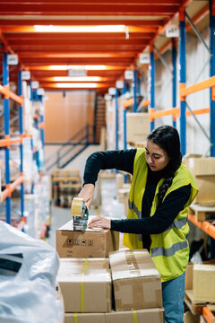 Woman sealing boxes with tape before shipping