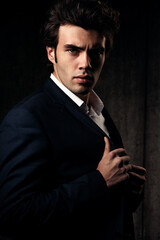 Fototapeta premium Charismatic handsome male in blue fashion suit and white style shirt sad looking down on dark shadow background. Closeup studio