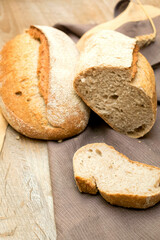 Assortment variety of baked crisp fresh bread, bun and baguette on wooden table with napkin, baking pastry food concept