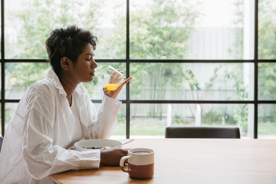 Young woman drinking orange juice at a dining table
