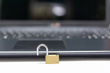 Laptop and open padlock in gold color (intentional blur)