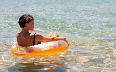 Middle aged woman relaxing on inflatable pool ring 