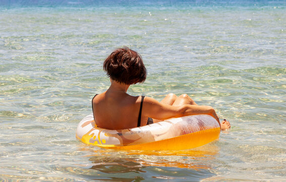 Back View Of Middle Aged Woman Relaxing On Pool Ring