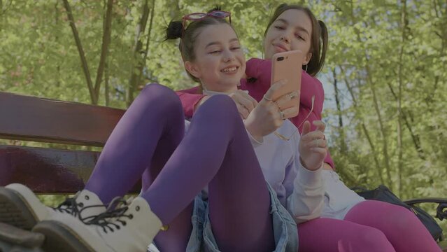 Two girls sit on a bench in an embrace and take a selfie together. girls who like each other.