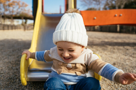 Cute toddler riding down slide on playground