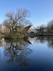 Fototapeta na wymiar Saniertes historisches Bauernhaus in einem Park am Teich in Bielefeld im Winter, Nordrhein-Westfalen, Deutschland 