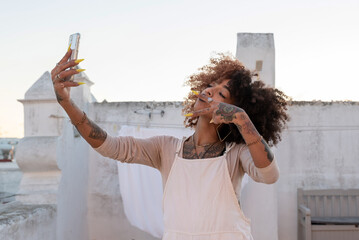 Stylish woman showing peace sign and taking selfie