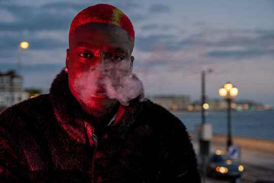 Trendy black man smoking e cigarette at night