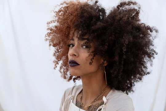 Stylish curly haired woman with golden accessories