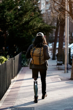 Stylish man with leg prosthesis walking on street